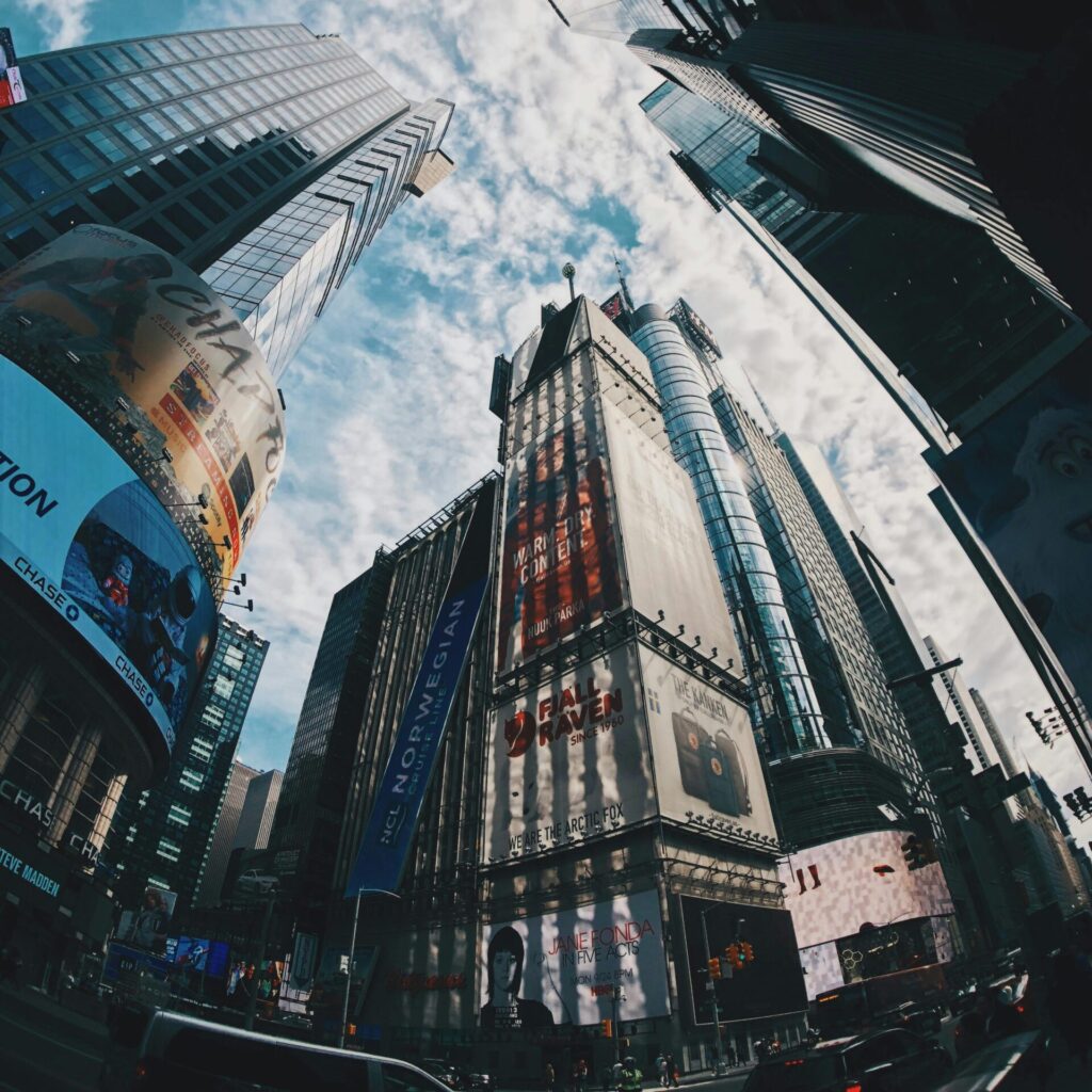 A striking fisheye view of skyscrapers under a bright sky in Times Square, NYC.